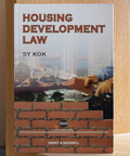 The image shows the cover of the book titled 'Housing Development Law' by S Y Kok. The cover features a construction site with a focus on a brick wall being built, and the title and author's name are displayed prominently at the top.